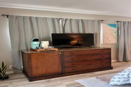 TV en un tocador de madera en un dormitorio en UNIT C - Sandy Toes Getaway in Kona, en Kailua-Kona