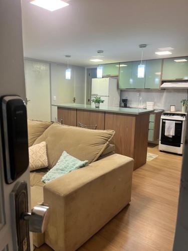 a living room with a couch and a kitchen at Incrível Apto 7 min do Aeroporto de GRU AR COND e GARAGEM in Guarulhos