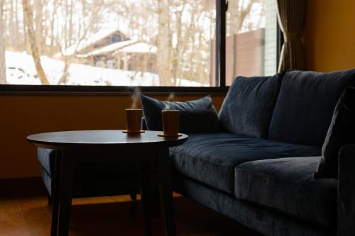 a living room with a blue couch and a table at 別邸　たてしな薫風 in Yukawa