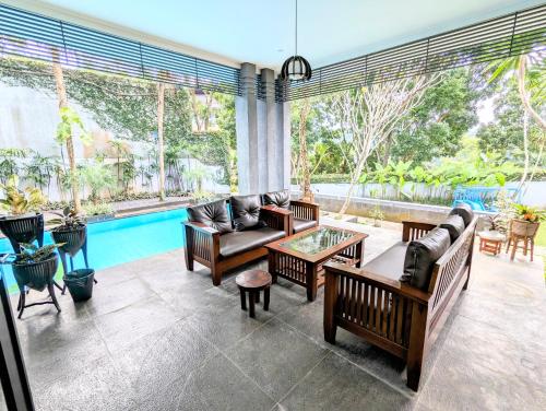 a living room filled with furniture and a swimming pool at Cottonwood Villa Mewah Nilaya @Dago - BBQ Pingpong in Bandung