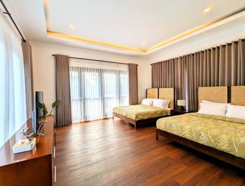 a hotel room with two beds and a television at Cottonwood Villa Mewah Nilaya @Dago - BBQ Pingpong in Bandung