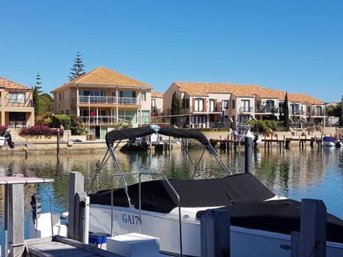 a boat is docked at a marina with houses at Dolphin Beach House - Wannanup, Mandurah between the estuary and the ocean in Wannanup