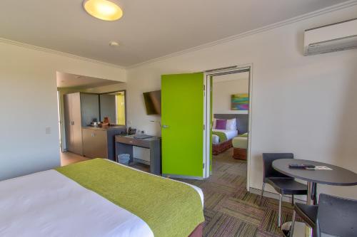 une chambre d'hôtel avec un lit et une porte verte dans l'établissement Mackay Oceanside Central Hotel Official, à Mackay