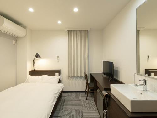 una habitación de hotel con una cama y un lavabo en オリエントホテルONOMICHI, en Kaneyoshi