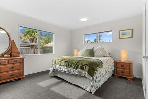 een slaapkamer met een bed, een dressoir en een spiegel bij Kaya-wai - Mangawhai Holiday Home in Mangawhai