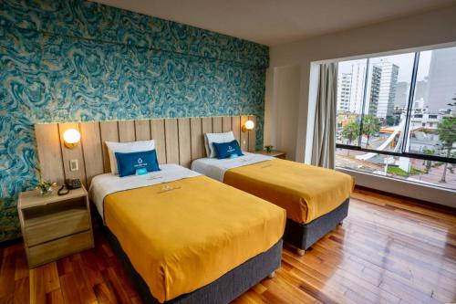 um quarto de hotel com duas camas e uma grande janela em Golden Mar Hotel em Lima