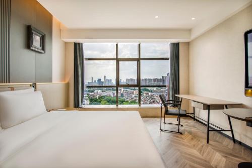 a bedroom with a bed and a desk and a window at Atour S Hotel Guangzhou Zhujiang Taikoocang in Guangzhou