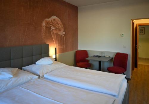 a bedroom with a bed and two red chairs at Pension Christine in Großweikersdorf