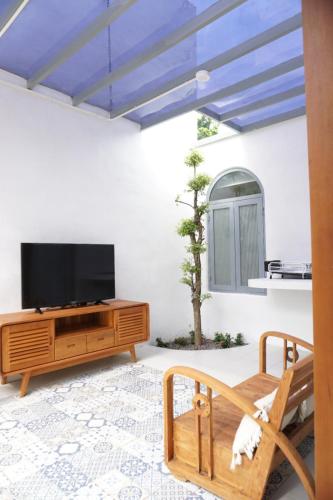 ein Wohnzimmer mit einem Flachbild-TV und einem Unterhaltungszentrum aus Holz in der Unterkunft LAYANA FARMSTAY in Banyuwangi