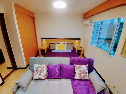 1 dormitorio con sofá y 1 cama con almohadas moradas en Hotel M-RCURE Vila Olímpia - The Best Smart Urban Duplex - Executive Edition - By LuXXoR en São Paulo
