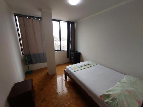 um quarto com uma cama e uma grande janela em Departamentos de la Costa em Machala
