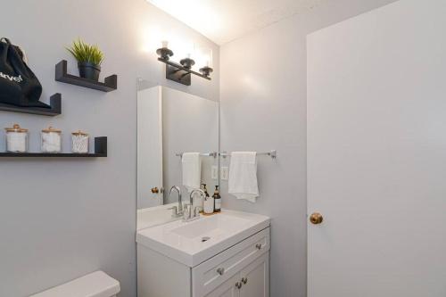 Baño blanco con lavabo y espejo en Cozy Downtown Oasis, en Hartford