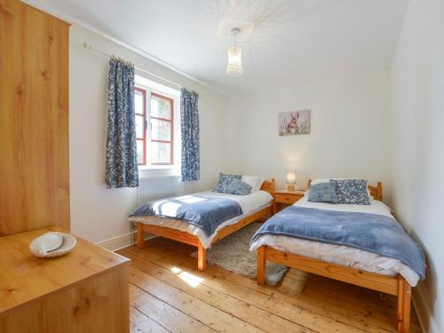 a bedroom with two beds and a window at Ludgate Cottage in Bovey Tracey