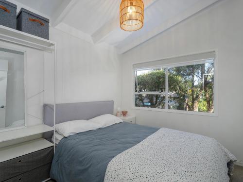 a white bedroom with a bed and a window at Sol Vista Paku - Pauanui Holiday Home in Pauanui
