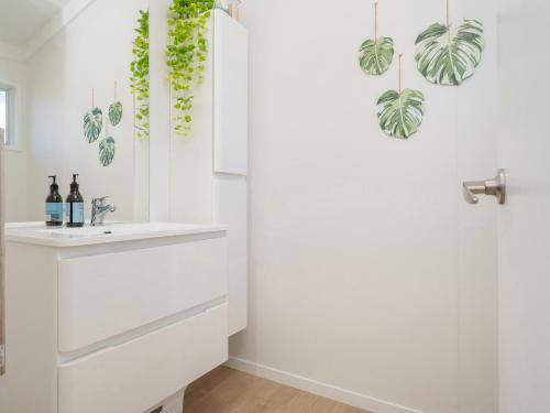 a bathroom with a sink and plants on the wall at Sol Vista Paku - Pauanui Holiday Home in Pauanui