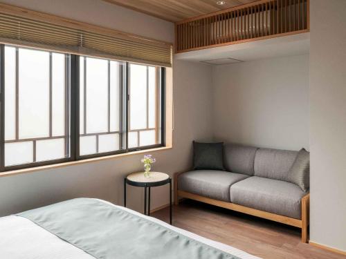 a bedroom with a bed and a couch and windows at Tokikaze Machiya House in Kanazawa