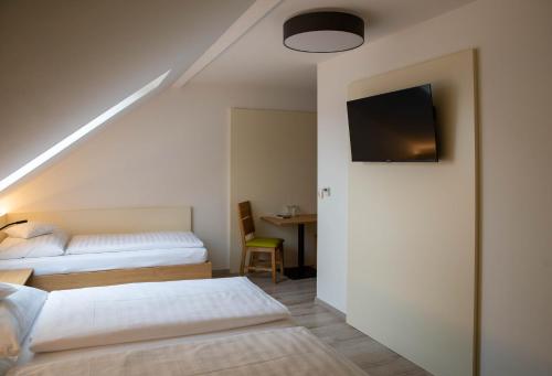a bedroom with two beds and a tv on the wall at Pension Christine in Großweikersdorf