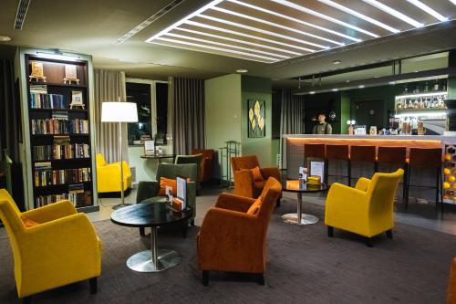 een bibliotheek met gele stoelen en een bar in het midden bij Park Hotel Almaty in Alma-Ata