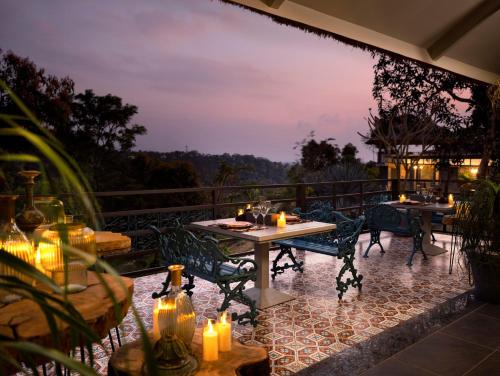 a patio with tables and chairs on a balcony at night at Blanket Days Resort and Spa in Thekkady
