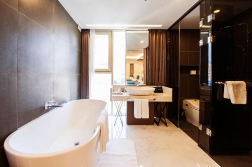 un baño con bañera y lavabo en Sweet May Seogwipo Hotel, en Seogwipo