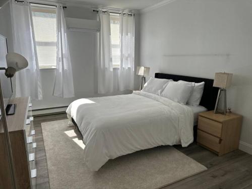 a white bedroom with a large bed and a window at Cozy 1BR Condo in West Hartford