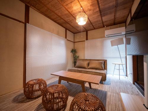 a living room with a couch and a table and stools at #14 -大垣 椛- 古民家の宿 大垣城まで車で10分 in Okoshi
