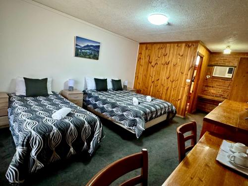 ein Hotelzimmer mit 2 Betten und einem Tisch in der Unterkunft Diamond House Heritage Restaurant and Motor Inn in Stawell