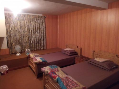 Cette petite chambre comprend 2 lits et une fenêtre. dans l'établissement 72 Khairagali, à Khaira Gali
