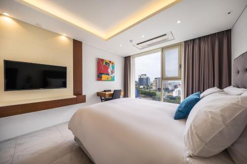 Habitación de hotel con cama grande y TV de pantalla plana. en Sweet May Seogwipo Hotel, en Seogwipo
