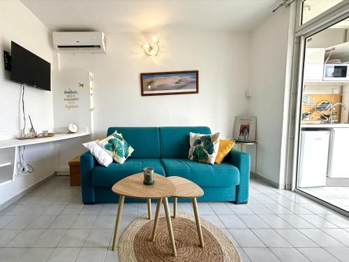 a living room with a blue couch and a table at La Kawannaise Blue Lagon - Wifi, Plage, Terrasse in Grand-Bourg