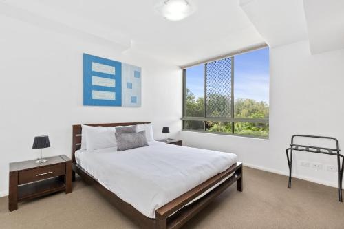 a bedroom with a bed and a large window at Beaches on Lammermoor Apartments in Yeppoon