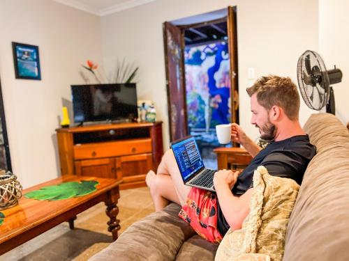 un uomo seduto su un divano con un portatile di Whitsundays BNB Retreat ad Airlie Beach