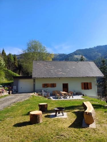 a building with a picnic table and logs in front of it at Ferienhaus Häusler in Sankt Erhard