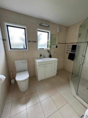 a bathroom with a toilet and a sink and a shower at Coastal Golf & Spa Guesthouse in Mount Maunganui