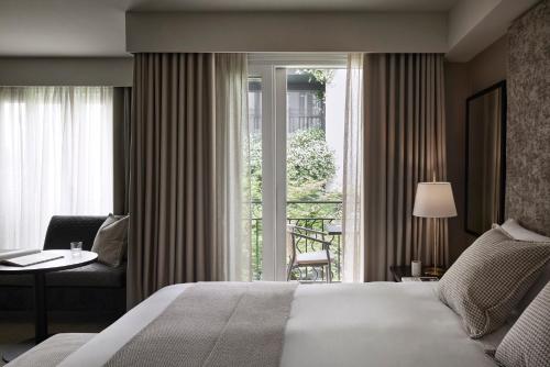 um quarto com uma cama, uma janela e uma cadeira em The Lyall em Melbourne