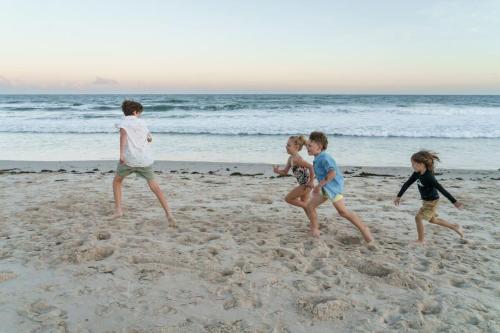 a group of children playing on the beach at Bright Stylish Kings Beach Apartment in Caloundra