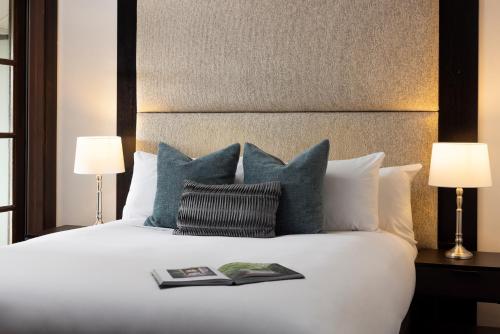 a bed with blue pillows and a book on it at Mineral Springs Hotel Hepburn in Hepburn Springs