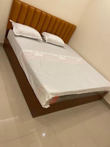 Una cama con sábanas blancas y almohadas. en Km mansion, en Chennai