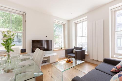 a living room with a glass table and a tv at Fitzrovia & Soho - 3BR - CityApartmentStay in London