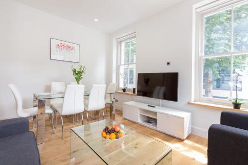a living room with a table and a television at Fitzrovia & Soho - 3BR - CityApartmentStay in London