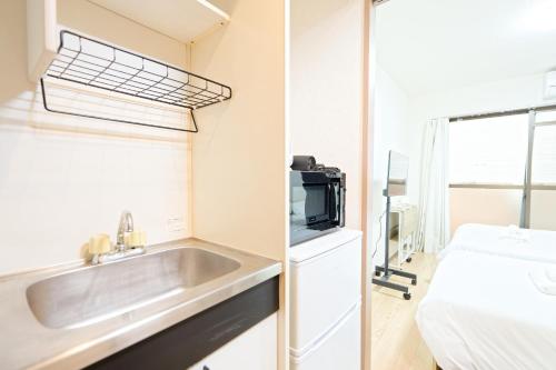 a small kitchen with a sink and a bed at Shinjuku Waseda Earthtone Apartment in Tokyo
