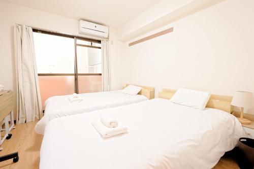 two white beds in a room with a window at Shinjuku Waseda Earthtone Apartment in Tokyo