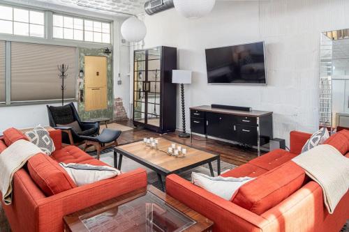 a living room with two orange couches and a tv at High-design Downtown Loft in Asheville