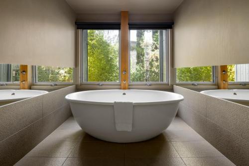 a large bathroom with three sinks and a large tub at Mineral Springs Hotel Hepburn in Hepburn Springs