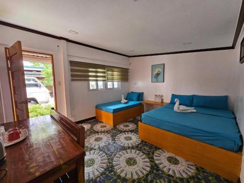 a bedroom with two beds with blue sheets and a table at Tambayan Rooms and Cottages by SMS Hospitality in Carmen