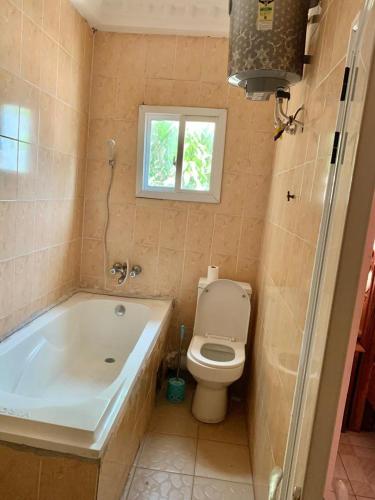 La salle de bains est pourvue de toilettes, d'une baignoire et d'une fenêtre. dans l'établissement Brufut Luxury Villa, à Brufut