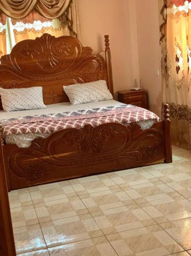 a large wooden bed with a wooden headboard in a bedroom at Brufut Luxury Villa in Brufut