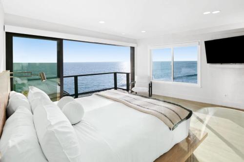a bedroom with a large white bed with a view of the ocean at Aquazzura - By Stay Awhile Villas in Malibu