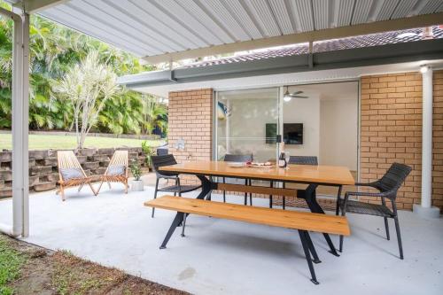 a patio with a wooden table and benches at Pet Friendly Battery Hill Home away from Home in Caloundra
