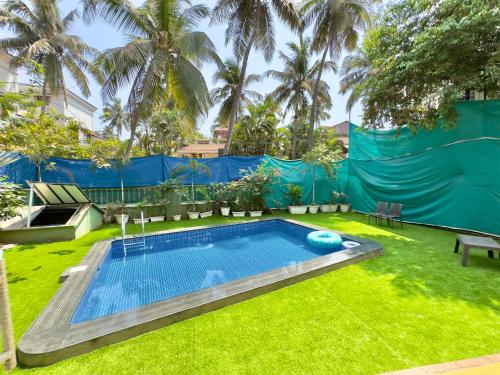 een zwembad in een tuin met gras en palmbomen bij Rustic Private Pool Villa # 8 by SAZJ Hospitality in Saligao